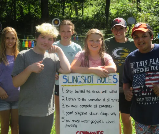 Leaders in training showing off their newly made slingshot rules board